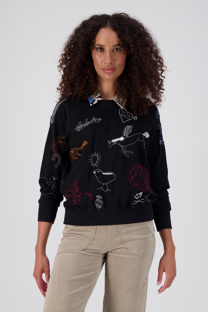 Black Olga de Polga Montage sweatshirt in a cotton tencel blend. The sweatshirt is embroidered with abstract motifs in a range of colours. Front view on model