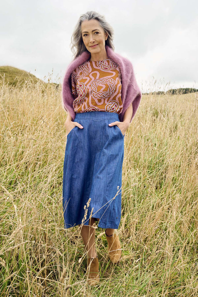 Olga de Polga new denim mid-wash Otago skirt in 100% cotton. An Asymmettrical skirt with a panelled front and side pockets.  Front view on model outdoors.