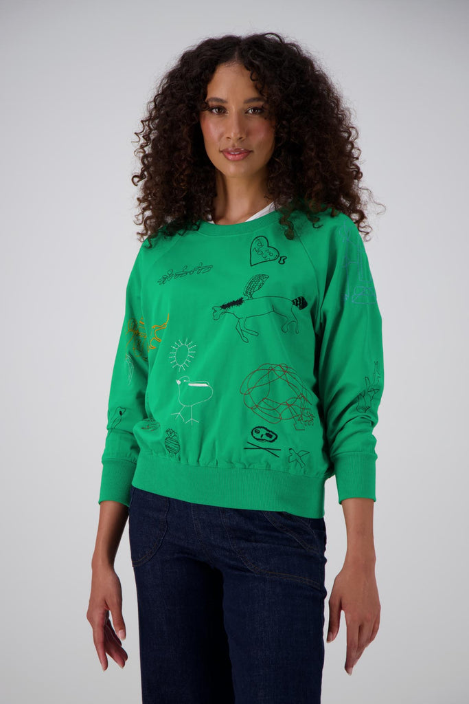Olga de Polga Green Montage sweatshirt in a cotton tence blend. The sweatshirt has abstract embroidered motifs. Ribbing at the neckline, cuffs and hem add durability to the sweatshirt. Front view on model