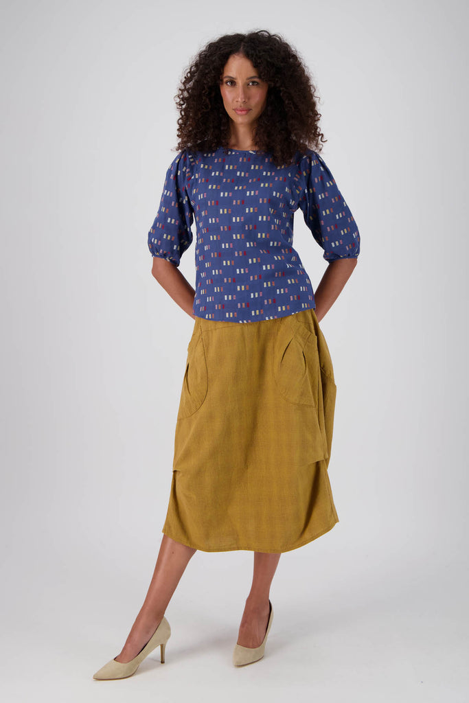 Olga de Polga Milwaukee Textured cotton skirt in Mustard. Best selling chic skirt in a unique cut with large patch pockets and an elasticated back waistband. Midi length. Front full length on model.