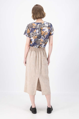 Olga de Polga Hepburn skirt in herringbone linen. Colour beige. Featuring a unique button detail at the waist that forms a flattering pocket shape, this skirt adds personality to any outfit. With an elasticated back waist for comfort, it finishes just below the knee and has a stylish back split for ease of movement. Back view on model.