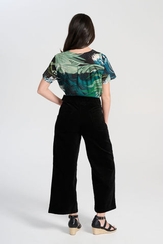 Olga de Polga Peggy Paris cropped wide leg pants in black soft velvet. Soft to the touch yet durable, the fabric drapes beautifully while maintaining its shape, making these pants ideal for cooler months. Back view on model