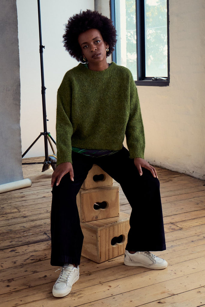 Olga de Polga Black Peggy Sue pants in cotton velvet corduroy. Comfortable high waist. Elastic waistband at the back. Front view on model sitting down.