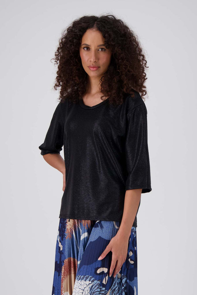 Olga de Polga Black Prosecco top in metallic polyester fabric. With a relaxed fit, scoop neckline, and 3/4 length sleeves, your everyday t-shirt now boasts a lustrous twist.  Side front view on model