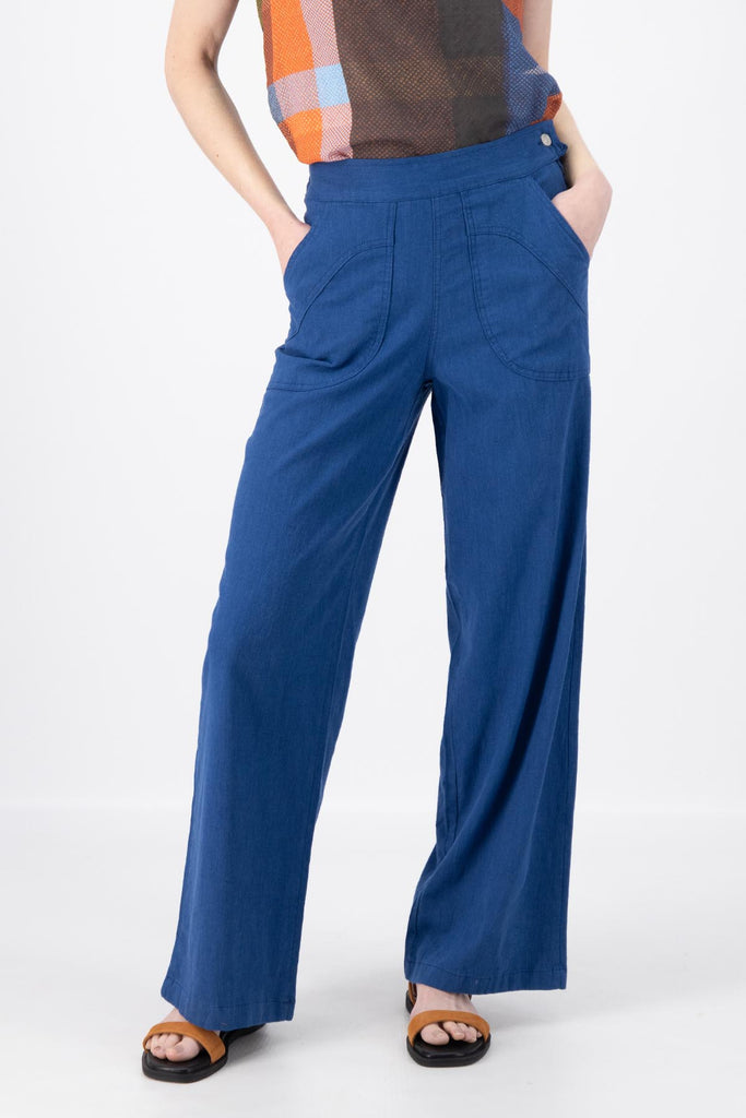 Olga de Polga Peggy Pants Long Lino in Cobalt Blue linen. Featuring a flattering high waist with an elasticated back, these pants provide all-day comfort while maintaining a sleek, streamlined look. With their stretchy wide-leg fit, flat front, and full-length silhouette, they effortlessly elevate any outfit. Front close-up view on model.