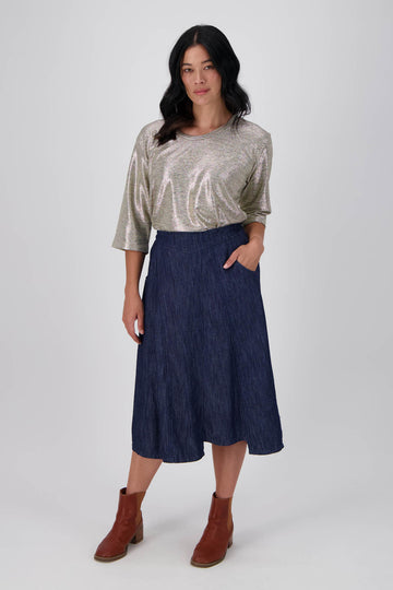 Olga de Polga dark denim Otago skirt. This A-symmetric dark denim skirt has a wide, flat front waistband and pockets. Front full length view on model