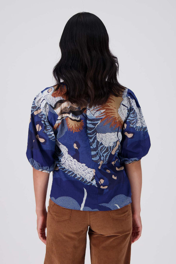 Olga de Polga's best selling Festival print is back in a new Blue colour way! The classic blouse with a round neckline and half length sleeves and an invisible back zip fastening.  Back view on model