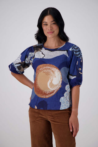 Olga de Polga's best selling Festival print is back in a new Blue colour way! The classic blouse with a round neckline and half length sleeves and an invisible back zip fastening. Front view on model. close up