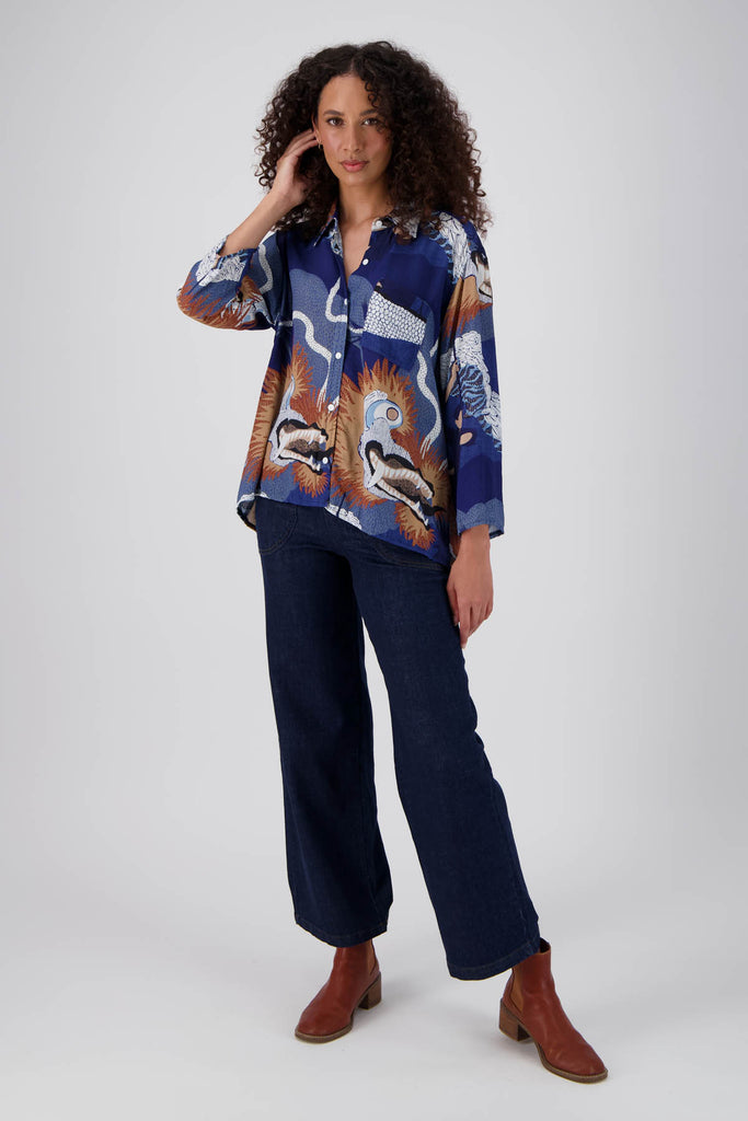 Olga de Polga classic shirt in the new Festival Blue print! Collar and button down front with 3/4 length sleeves which can be rolled up and buttoned. Shirt is longer at the back. Front view on model