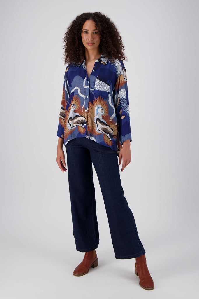 Olga de Polga classic shirt in the new Festival Blue print! Collar and button down front with 3/4 length sleeves which can be rolled up and buttoned. Shirt is longer at the back. Front full length view on model