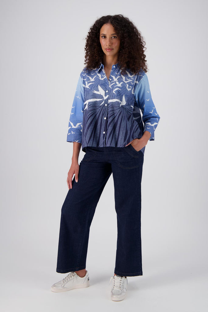 Olga de Polga Blue Homebound printed cotton shirt. With 3/4 length sleeves and a collar with a button down front, this shirt has an oversized fit with a trapeze shape. Waist length at the front with the back is hip length creating a lovely drape. Front full length view on model