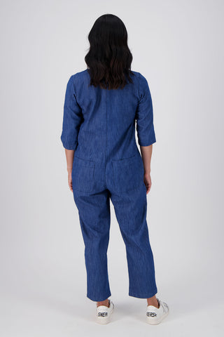 Olga de Polga Blue mid-wash denim Artisan Jumpsuit in cotton denim. Half sleeves and a button down front with patch pockets. Ankle length.  Back full length view on model