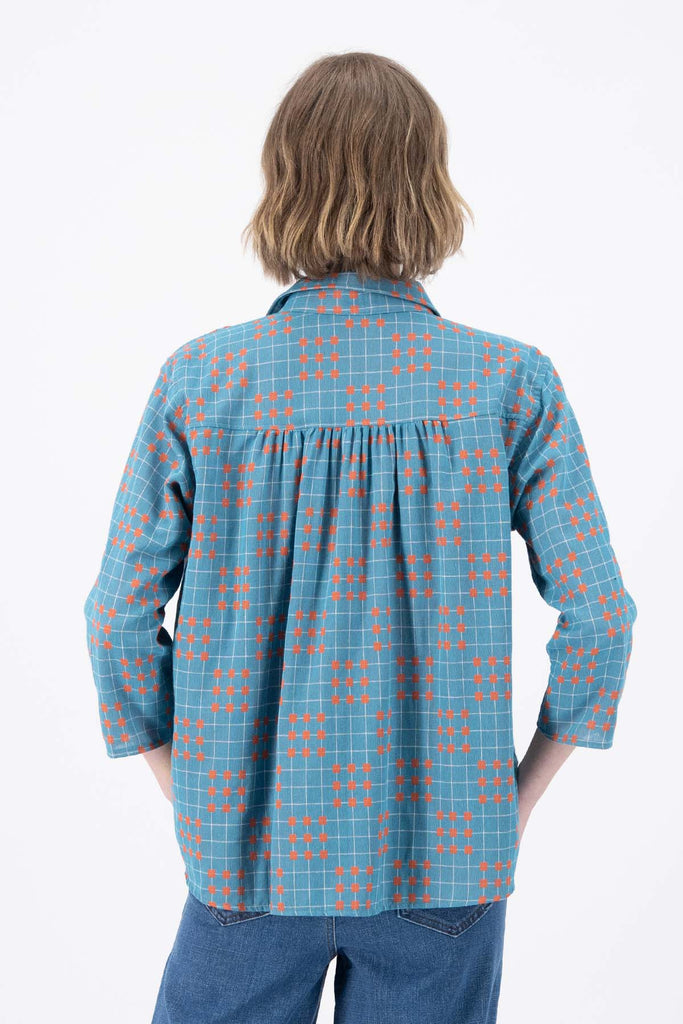 Olga de Polga Blue printed Network shirt in cotton. Soft, lightweight, floaty fabric. 3/4 sleeves. Front button opening with collar. Oversized shirt with gathering on the back. Back view on model.