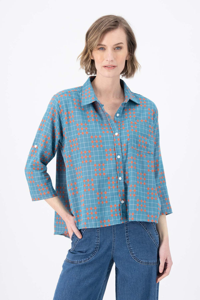 Olga de Polga Blue printed Network shirt in cotton. Soft, lightweight, floaty fabric. 3/4 sleeves. Front button opening with collar. Oversized shirt with gathering on the back. Front view on model.