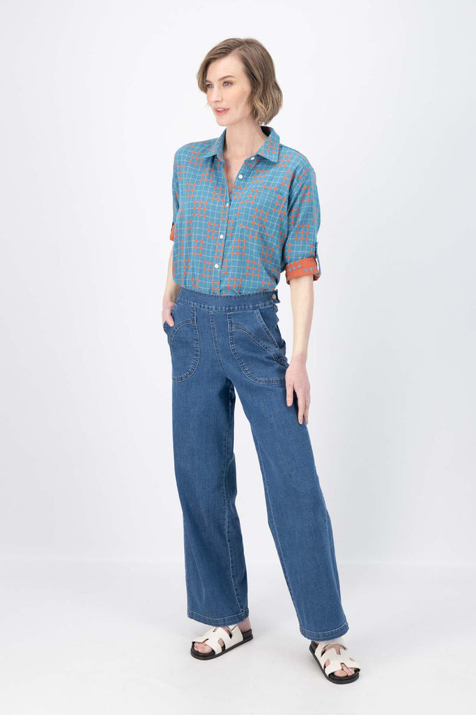 Olga de Polga Blue printed Network shirt in cotton. Soft, lightweight, floaty fabric. 3/4 sleeves. Front button opening with collar. Oversized shirt with gathering on the back. Side front view on model.