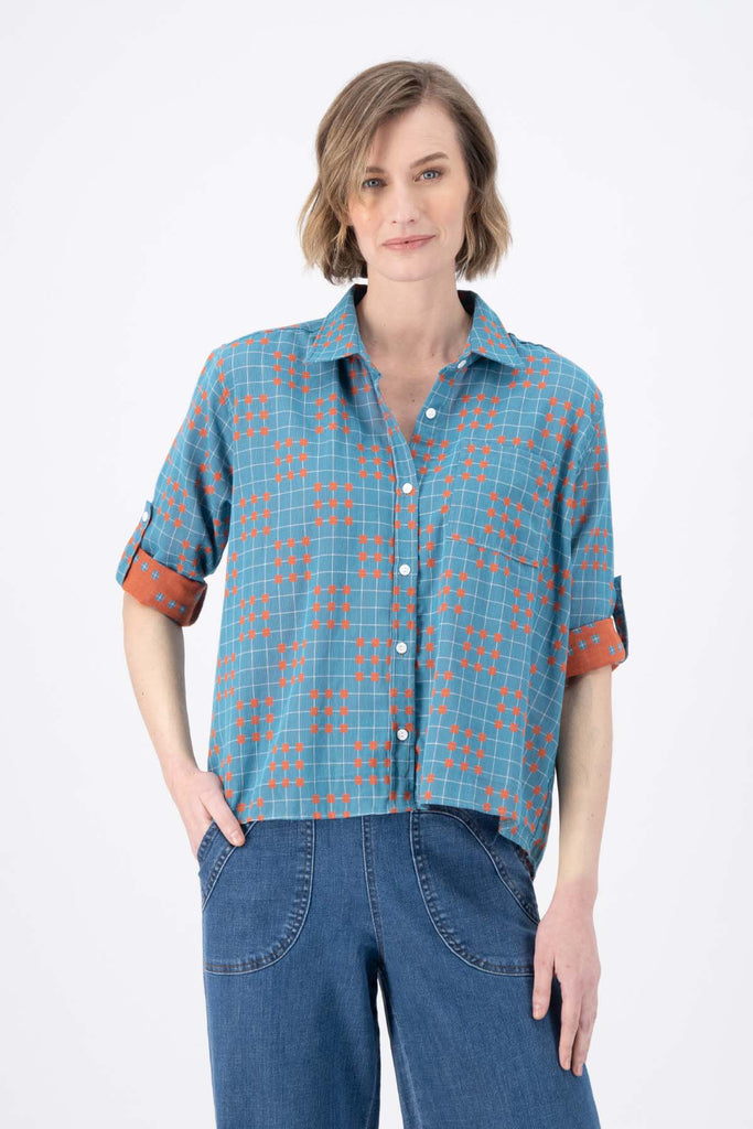 Olga de Polga Blue printed Network shirt in cotton. Soft, lightweight, floaty fabric. 3/4 sleeves. Front button opening with collar. Oversized shirt with gathering on the back. Front view with rolled up sleeves on model.