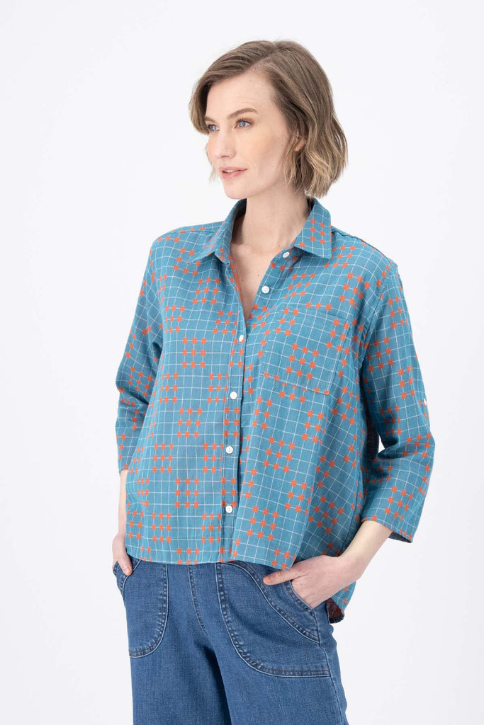 Olga de Polga Blue printed Network shirt in cotton. Soft, lightweight, floaty fabric. 3/4 sleeves. Front button opening with collar. Oversized shirt with gathering on the back. Side view on model.