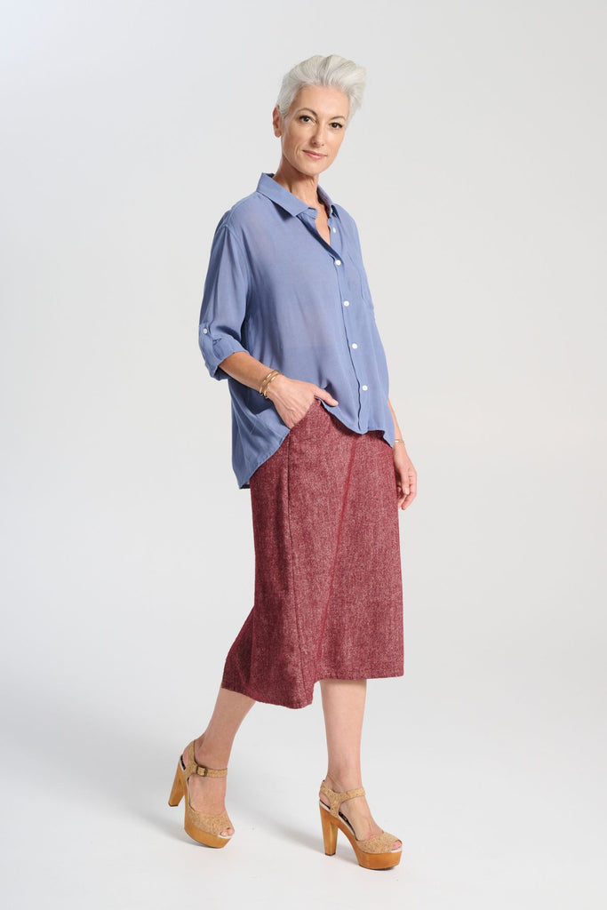 Olga de Polga Smokey Blue Ava shirt in mid-weight viscose crepe. With a button down front and collar, 3/4 sleeves with an option to fasten half way up. Front finishes at the waist and the back drapes down lower to the hip. side front view on model