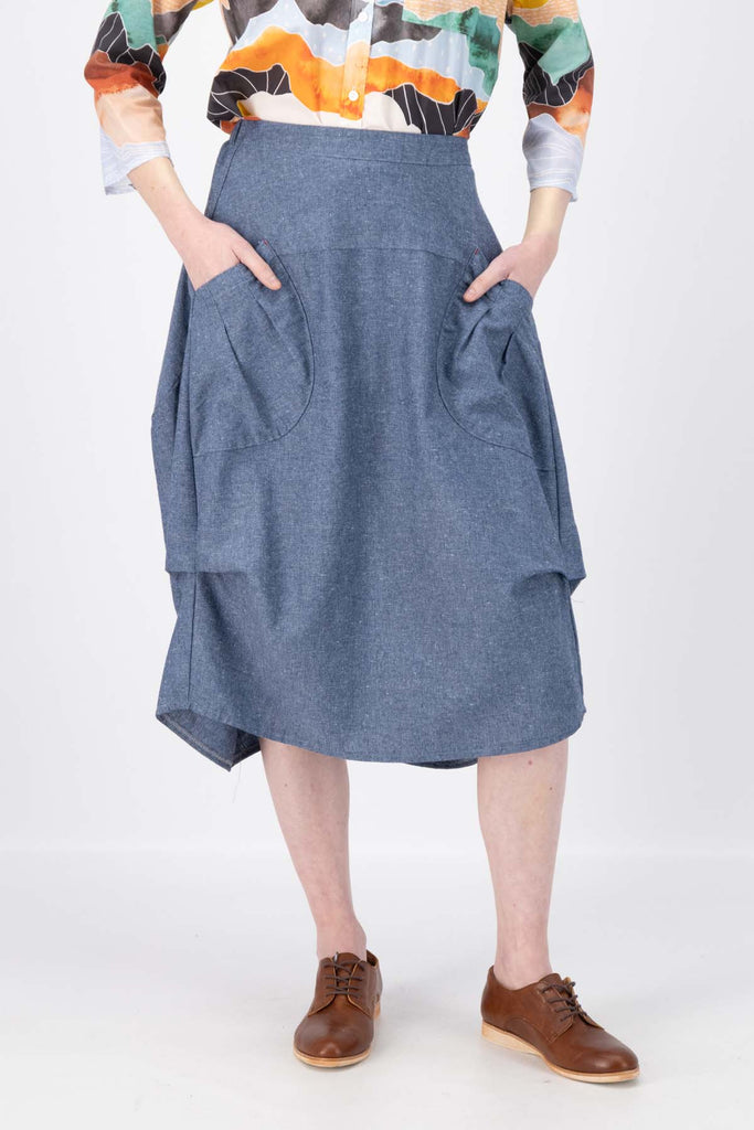 The Milwaukee Traveller skirt in Stone Blue cotton, linen, Tencel blend. The Milwaukee is an incredibly unique, chic and original skirt. It is universally flattering, highly versatile, and super comfortable. Perfect to throw on and go. Front close-up view on model