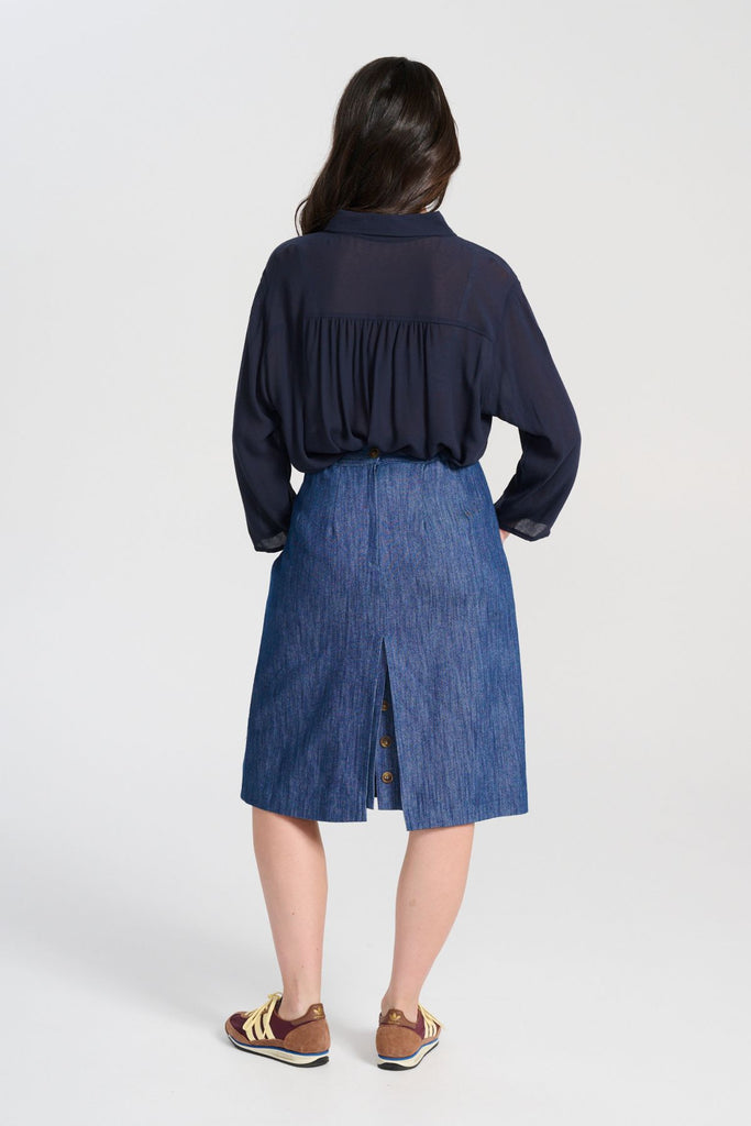 Olga de Polga Upper Eastside skirt, back view on model. Knee length skirt with a back split. Flat front waistband. Elasticated panels in the waistband for a flexible fit.