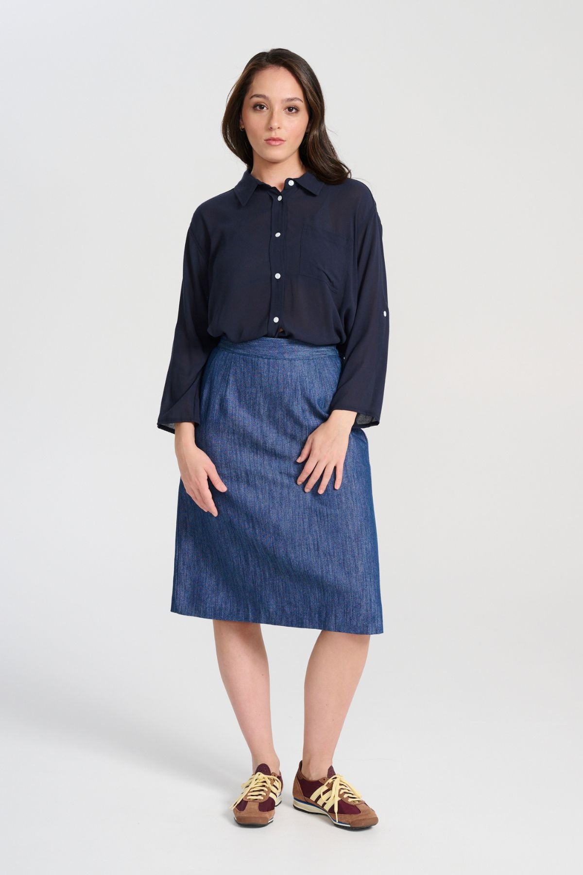 Olga de Polga Upper Eastside skirt, front view on model. Knee length skirt with a back split. Flat front waistband. Elasticated panels in the waistband for a flexible fit.