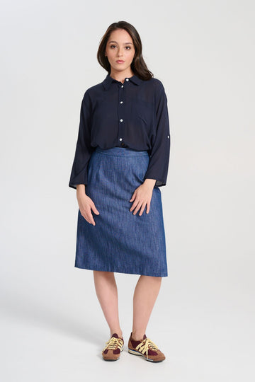 Olga de Polga Upper Eastside skirt, front view on model. Knee length skirt with a back split. Flat front waistband. Elasticated panels in the waistband for a flexible fit.