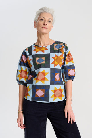Olga de Polga printed blouse in Veda Day cotton. The blouse features a beautifully detailed lantern sleeve with a drop shoulder and delicate pleating on the shoulder and cuff. It also has a wide boat neckline and invisible zip fastening at the back. Front view on model