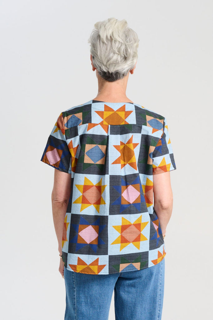 Olga de Polga Veda Day Top in printed cotton. Light blue background with geometric shapes. Round neckline, Short sleeves. Back view on model