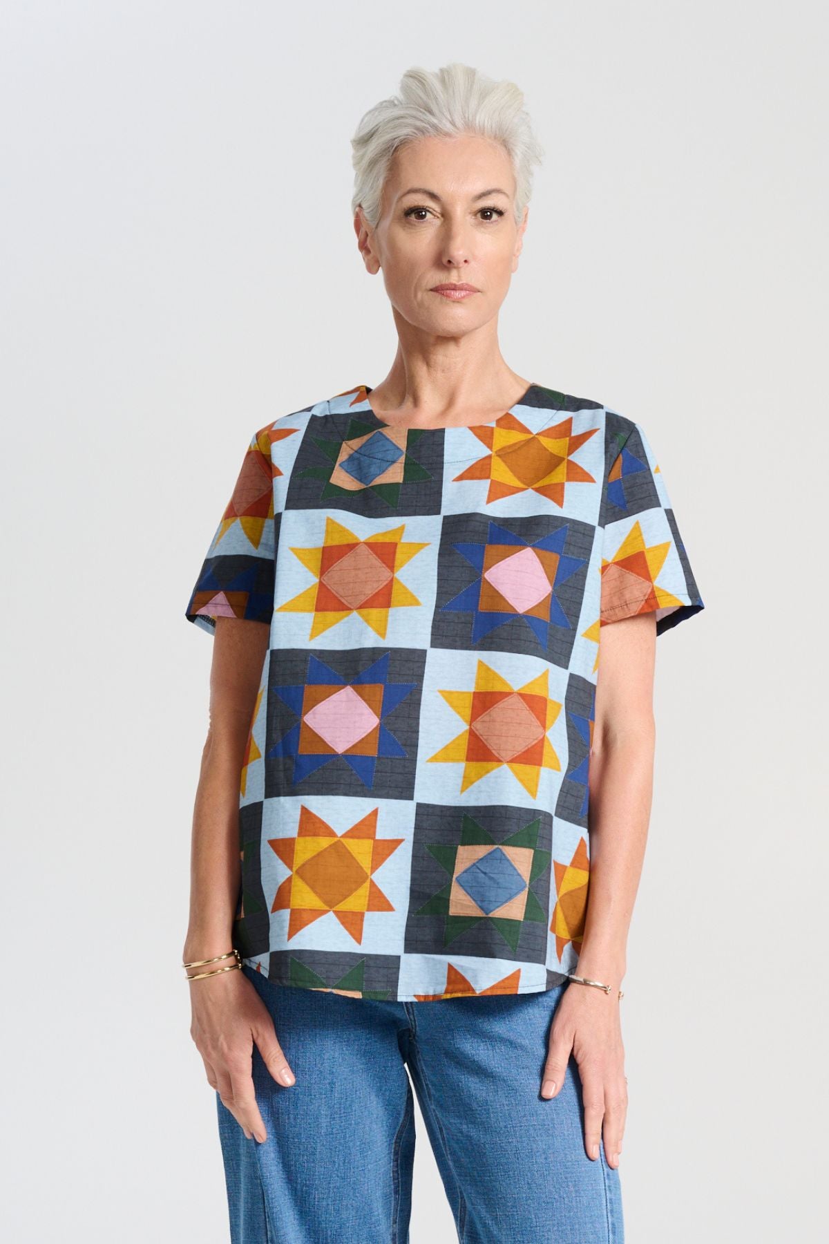 Olga de Polga Veda Day Top in printed cotton. Light blue background with geometric shapes. Round neckline, Short sleeves. Front view on model