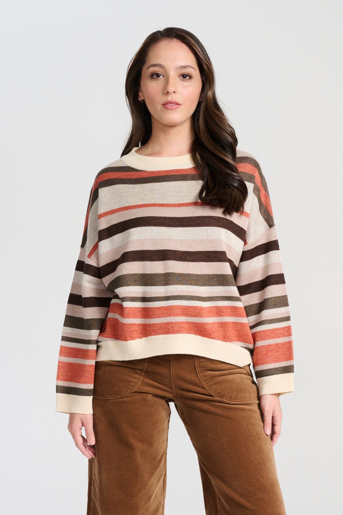 Olga de Polga Brown Earth Colorado Knit sweater with stripes in earthy colours of cream, coral, beige and brown. Long sleeves, dropped shoulders, round neckline. Front close-up view on model.