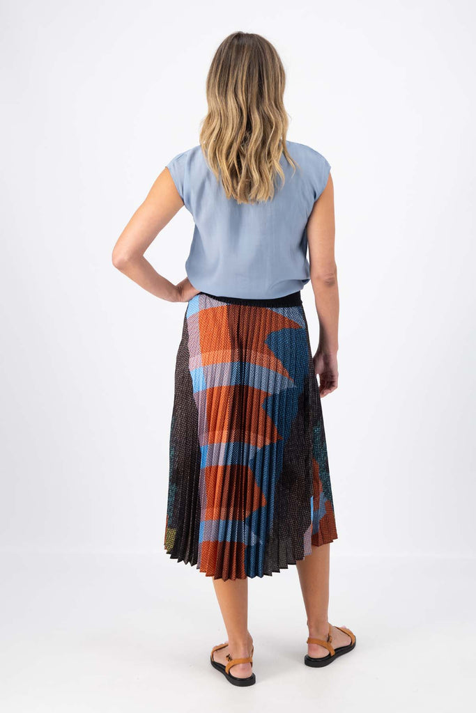 Olga de Polga pleated skirt in the Jada print. Colours of Umber, orange and cobalt blue shine in this print Elasticated waistband. Midi length. Back view on model.