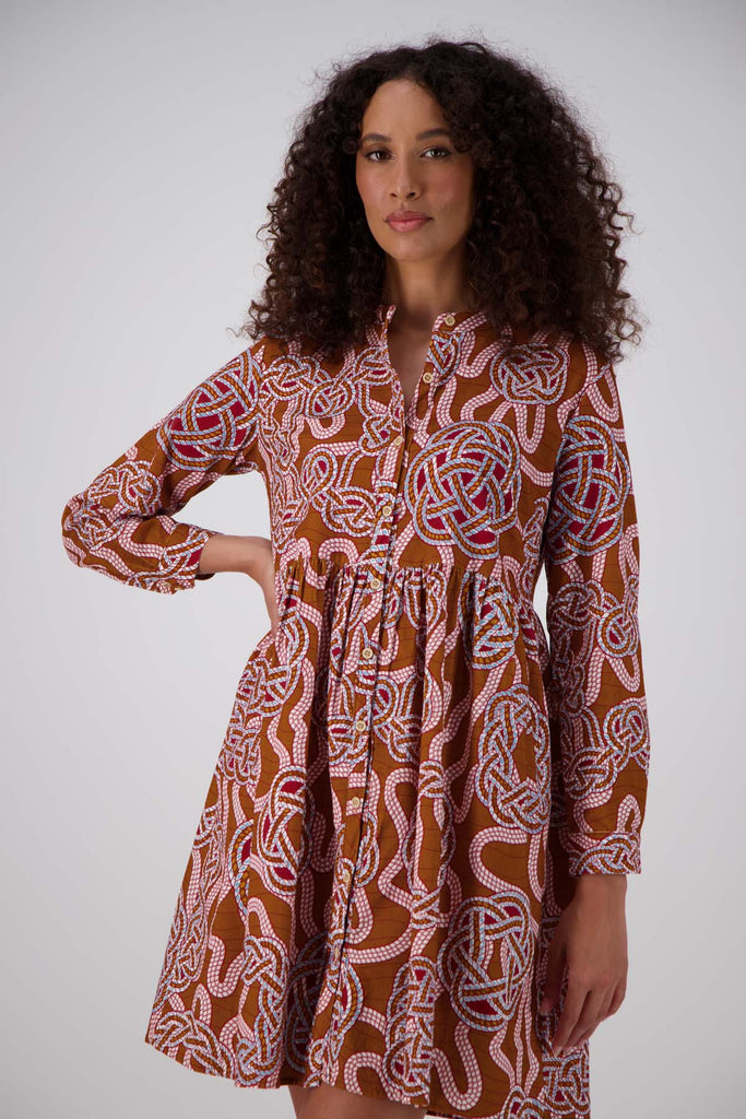 Olga de Polga new tunic dress in fine cotton cord. In the love knots print. -More than just a print, "Love Knots" is a visual ode to the enduring power and beauty that emanate from the intertwined twists and turns of love's journey. Wear it as a heartfelt expression, a fashionable reminder of the meaningful ties that enrich your life. Front view on model