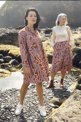 Olga de Polga new tunic dress in fine cotton cord. In the love knots print. -More than just a print, "Love Knots" is a visual ode to the enduring power and beauty that emanate from the intertwined twists and turns of love's journey. Wear it as a heartfelt expression, a fashionable reminder of the meaningful ties that enrich your life. Side front view outdoors