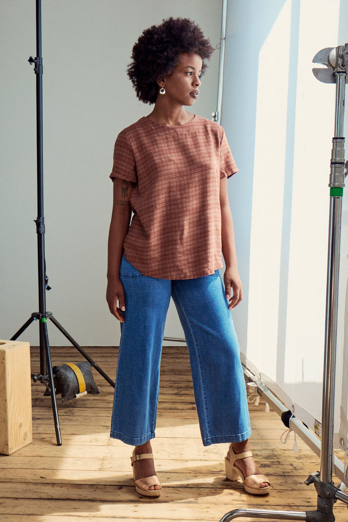 Olga de Polga Mocha brown top in brushed cotton seersucker. A little more modest and roomy than the tee, it is a straight cut, with a short sleeve, crew neck and a box pleat at the back to give it more fullness and movement. Side front view on model