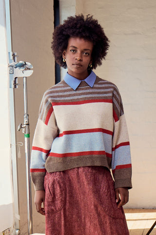 Olga de Polga Brown Paloma Sweater. A striped sweater with browns, cream, red and pale blue. front view on model close up.