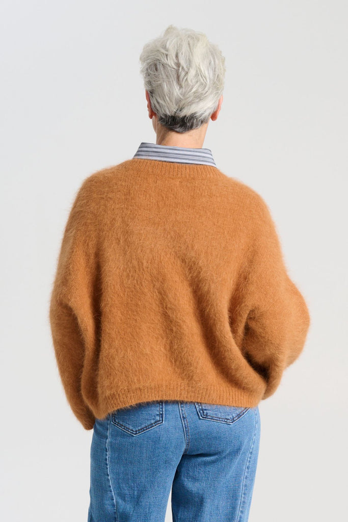 Olga de Polga angora Montreal knit sweater in Caramel brown. he knit features a ribbed round neckline, drop shoulder and cropped length, so it is perfect with jeans and skirts. The fit is slightly oversized with a boxy cut and long sleeves. Back view on model