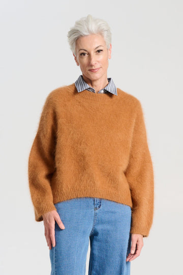 Olga de Polga angora Montreal knit sweater in Caramel brown. he knit features a ribbed round neckline, drop shoulder and cropped length, so it is perfect with jeans and skirts. The fit is slightly oversized with a boxy cut and long sleeves. Front close up view on model.