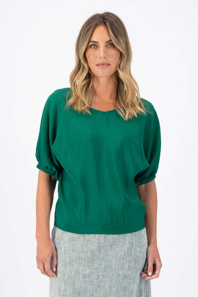 The Camisa blouse in Dark Green Tencel is a bat-winged blouse with short sleeves and is great for everyday wear. This style can be dressed up or down. This blouse will take you from work to weekend and beyond! Front view on model.