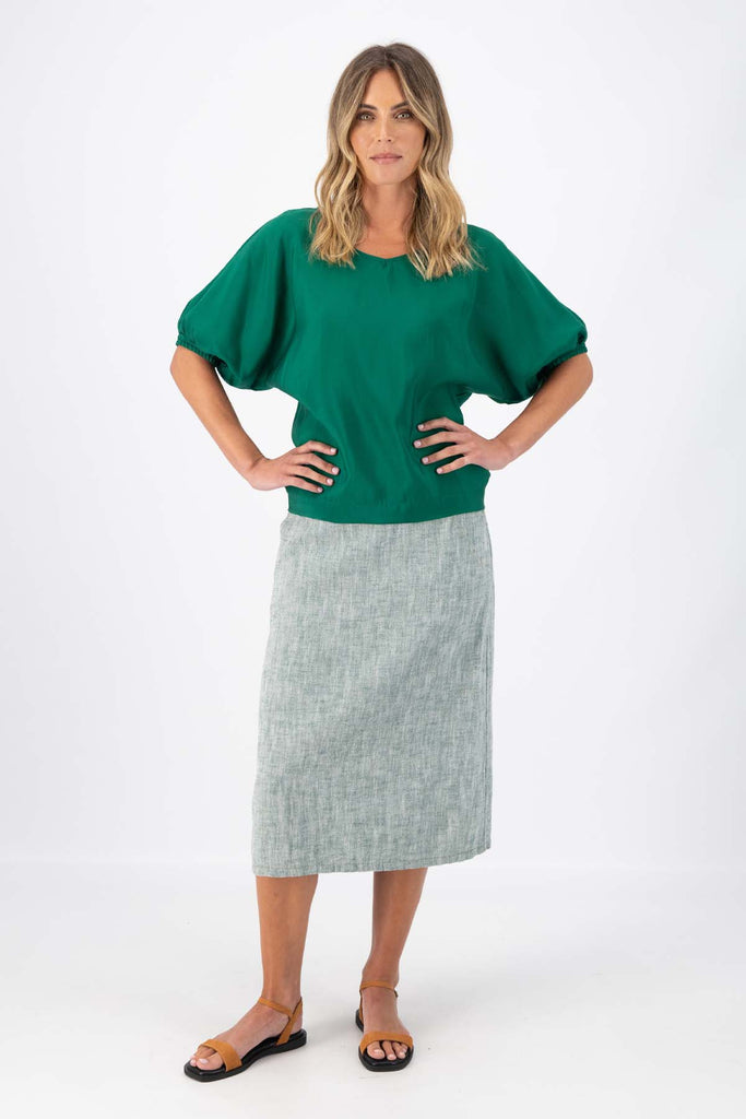 The Camisa blouse in Dark Green Tencel is a bat-winged blouse with short sleeves and is great for everyday wear. This style can be dressed up or down. This blouse will take you from work to weekend and beyond! Front full length view on model.