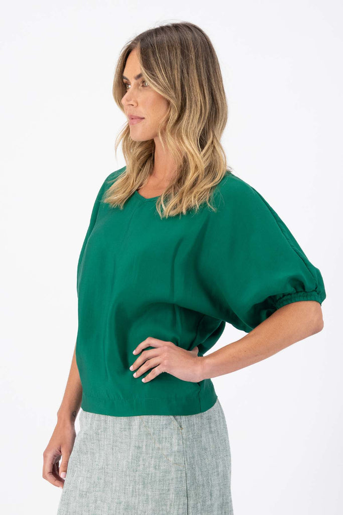 The Camisa blouse in Dark Green Tencel is a bat-winged blouse with short sleeves and is great for everyday wear. This style can be dressed up or down. This blouse will take you from work to weekend and beyond! Side view on model.