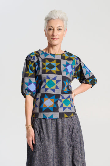 Olga de Polga Veda Blouse Night in printed cotton.  The blouse features a beautifully detailed lantern sleeve with a drop shoulder and delicate pleating on the shoulder and cuff. It also has a wide boat neckline and invisible zip fastening at the back. Front view on model