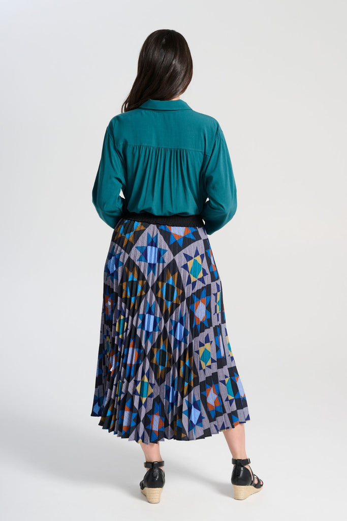 Olga de Polga Pleated Veda Night skirt in printed recycled polyester. Our pleated skirts are comfortable and functional enough to wear for every occasion, with the pleats creating beautiful movement with each step, with a fully elasticated waistband. Back view on model