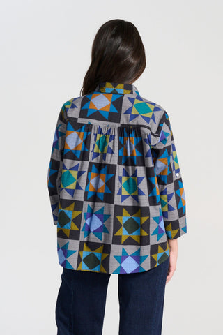 Olga de Polga Veda Shirt in Night printed cotton. Front view on model. It has an effortlessly chic, relaxed silhouette that drapes with ease. Leave it loose or tuck it in - the choice is yours.
The front of the shirt sits at the waist while the back falls to the hips for a lovely drape. Back view on model