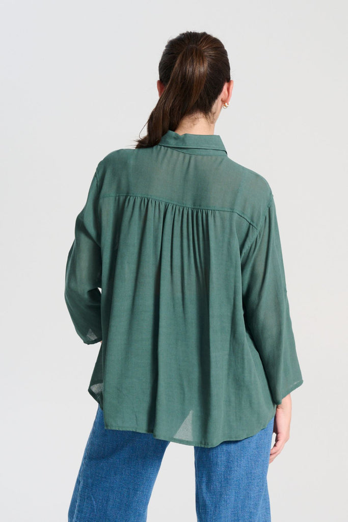 Olga de Polga Forest Green Ava Shirt in soft viscose crepe. he signature Olga Shirt is great for all occasions. It has an effortlessly chic, relaxed silhouette that drapes with ease. Leave it loose or tuck it in - the choice is yours.
The front of the shirt sits at the waist while the back falls to the hips for a lovely drape. Roll-up sleeve option with button. Back view on model