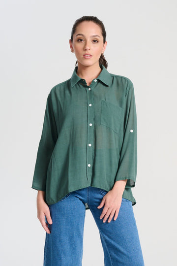 Olga de Polga Forest Green Ava Shirt in soft viscose crepe. he signature Olga Shirt is great for all occasions. It has an effortlessly chic, relaxed silhouette that drapes with ease. Leave it loose or tuck it in - the choice is yours.
The front of the shirt sits at the waist while the back falls to the hips for a lovely drape. Roll-up sleeve option with button. Front view on model.