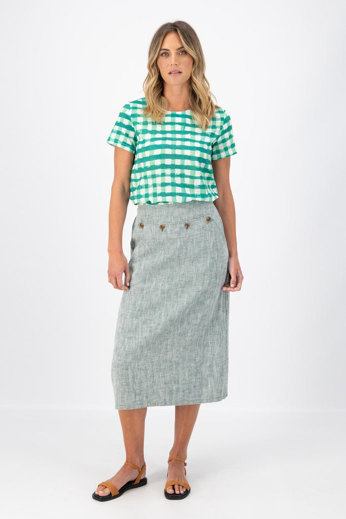 Olga de Polga Green Hepburn skirt in herringbone linen. A pencil skirt with a twist.  Featuring a unique button detail at the waist that forms a flattering pocket shape, this skirt adds personality to any outfit. With an elasticated back waist for comfort, it finishes just below the knee and has a stylish back split for ease of movement. Front view on model.