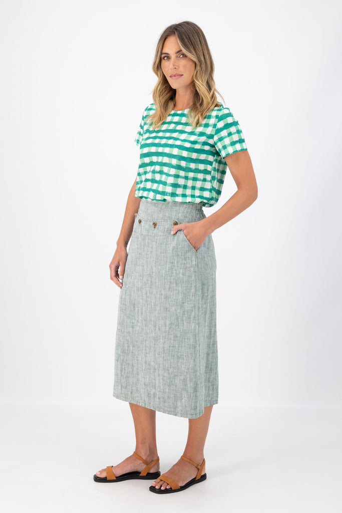 Olga de Polga Green Hepburn skirt in herringbone linen. A pencil skirt with a twist.  Featuring a unique button detail at the waist that forms a flattering pocket shape, this skirt adds personality to any outfit. With an elasticated back waist for comfort, it finishes just below the knee and has a stylish back split for ease of movement. Side view on model.