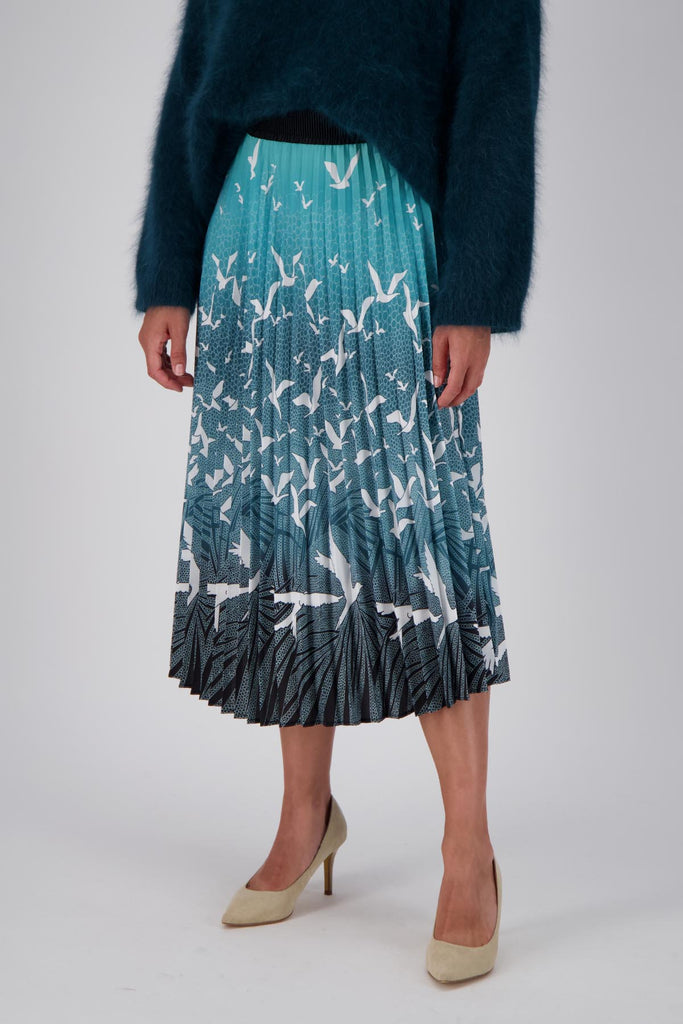 Olga de Polga pleated skirt in our new print, Homebound Green. Dive into the graceful movement of "Homebound," where the enchanting dance of a flock of birds takes centre stage. Capturing the spirit of returning to the heart of home, this print symbolises a journey, a reunion, and the comforting embrace of familiar skies. Front close up view on model