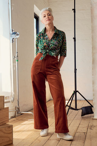 Olga de Polga Green Kaleidoscope cotton printed button-up shirt. Front full length view on model. Shirt is tied at the front. It can be left to hang loose.