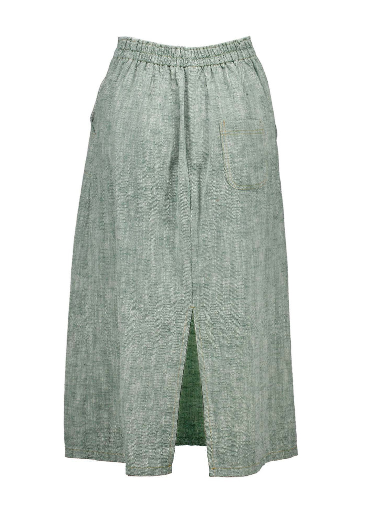 Olga de Polga Green Hepburn skirt in herringbone linen. A pencil skirt with a twist.  Featuring a unique button detail at the waist that forms a flattering pocket shape, this skirt adds personality to any outfit. With an elasticated back waist for comfort, it finishes just below the knee and has a stylish back split for ease of movement. Front view.